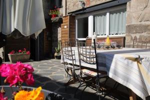 a patio with a table and chairs and a window at Chambre Les Embruns, Le Petit Ruban in Saint-Just-Malmont