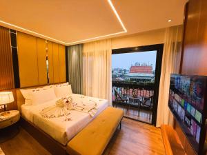 ein Schlafzimmer mit Bett, Fernseher und Balkon in der Unterkunft Casa Valentina Hanoi Hotel in Hanoi