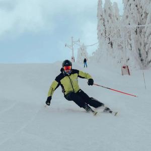 a man is skiing down a snow covered slope at Studio Apartment ViS in Residence Hill Kopaonik in Kopaonik