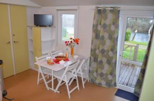 a dining room with a table and chairs and a television at ZEcamping 4 étoiles parc aquatique restaurant et parcours de pêche au fouet in Argentat