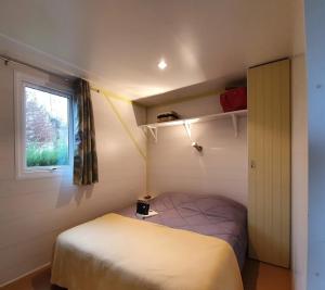 a small bedroom with a bed and a window at ZEcamping 4 étoiles parc aquatique restaurant et parcours de pêche au fouet in Argentat