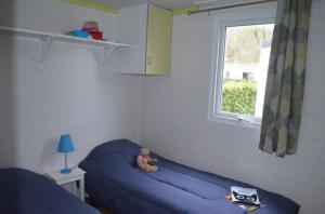 a teddy bear sitting on a blue bed in a room at ZEcamping 4 étoiles parc aquatique restaurant et parcours de pêche au fouet in Argentat +46 photos