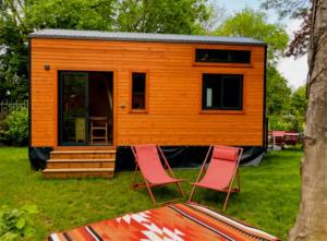 a tiny house on the grass with two chairs at Cabane 3 étoiles - ccbechc in Neuilly-sur-Marne