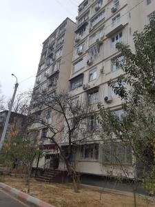 Center-Train Station-Airport في Toshkent-Passajir Bekati: مبنى ابيض طويل وامامه شجرة