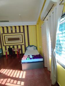 a small bedroom with a bed and a window at Trishan Hotel in Dhupguri