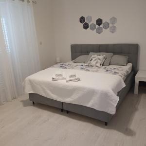 a bedroom with a bed with a white bedspread and two towels at Apartments Duras in Gruda