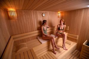 two girls are sitting in a sauna at The Central City - Luxury Serviced Residence in Luxembourg