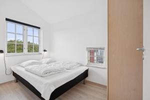 Feriehus 3007 في Nørre Lyngvig: سرير في غرفة بيضاء مع نافذة