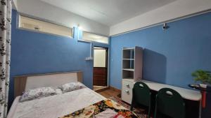 Songden Homestay في Kurseong: غرفة نوم بجدران زرقاء وسرير ومكتب