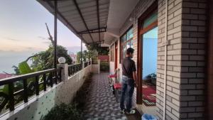 Songden Homestay في Kurseong: رجل يقف على شرفة منزل