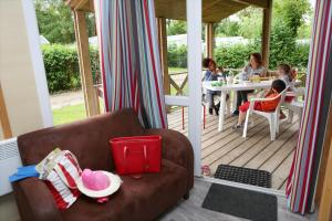 a group of children sitting at a table on a porch at Camping Le Val de Trie in Béhen