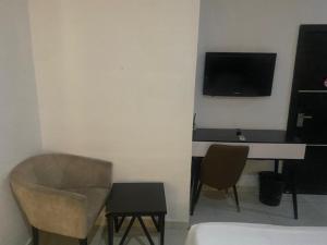 a room with a desk and a television and a chair at Modex Hotel in Mama