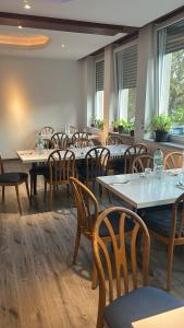 a dining room with tables and chairs and windows at Hotel RI in Esslingen