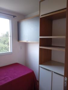 Habitación pequeña con cama y armario en Apartamento dentro da ucs universidade, en Caxias do Sul