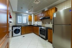 a kitchen with wooden cabinets and a stainless steel refrigerator at Havana Holiday Homes Oud Metha in Dubai