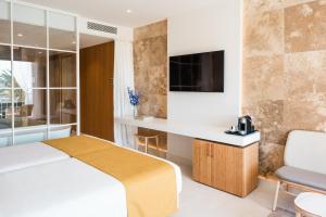 a bedroom with a bed and a desk and a tv at Aguas de Ibiza Grand Luxe Hotel - Small Luxury Hotel of the World in Santa Eularia des Riu +85 photos