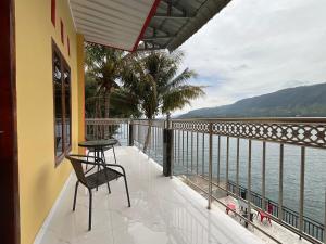 a balcony with a chair and a view of the water at Penginapan Mafir in Tuk Tuk