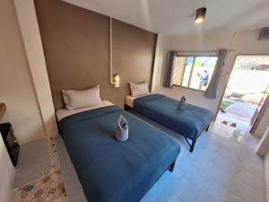 two beds in a room with blue sheets at So Good in Pai