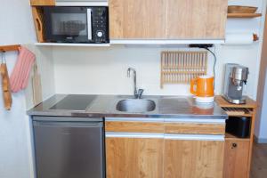 Una pequeña cocina con fregadero y microondas. en Studio 1 chambre pied des pistes 24 m2, en Risoul
