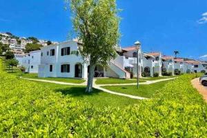 a row of houses with a tree in the yard at SON BOU Apartamento en planta baja junto la playa in Son Bou