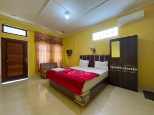 a bedroom with a large bed with a red blanket at Penginapan Mafir in Tuk Tuk