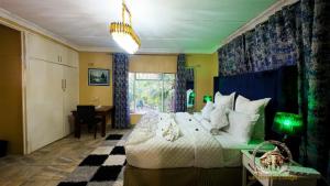 a bedroom with a bed and a desk and a window at uPhondo Lodge in Bulawayo +151 photos