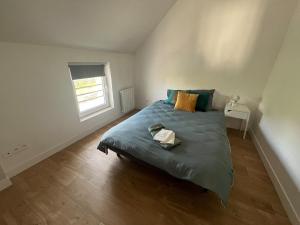 a bedroom with a bed with a green comforter and a window at Magnifique logement indépendant avec sa place de parking in La Celle-sous-Gouzon