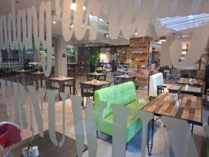 a restaurant with tables and chairs and a green chair at Meotel Purwokerto in Purwokerto