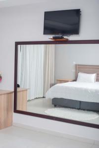 een spiegel die een slaapkamer reflecteert met een bed en een tv bij Palm Leaf – Hazeldene Kwekwe with pool - 2333 in Kwekwe