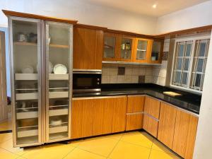 a kitchen with wooden cabinets and black counter tops at Queens Homestay in Trivandrum