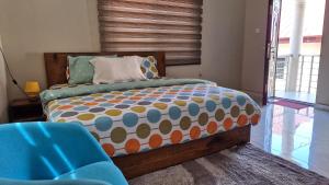 a bedroom with a bed and a blue chair at Aratina Apartments in Sunyani