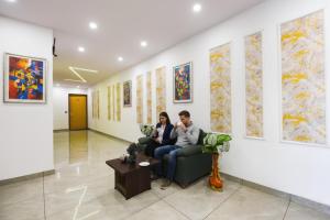 a man and woman sitting on a couch in a room at FabHotel AB Residency in Ludhiana
