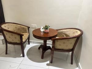 a wooden table with two chairs and a table with flowers at Aratina Apartments in Sunyani