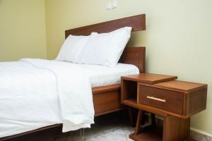 a bed with a wooden headboard next to a night stand at Résidence Romacy, appartement 2 chambres avec balcon à Ahala, quartier résidentiel de Yaoundé in Yaoundé +6 photos