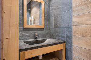 een badkamer met een wastafel en een spiegel bij Chalet Salt Lake in La Toussuire