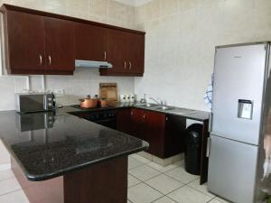 a kitchen with brown cabinets and a white refrigerator at 54 Topanga Holiday Accommodation in Margate