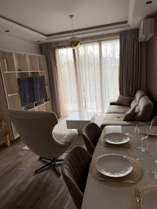 een woonkamer met een bank, een tafel en stoelen bij Апартамент AZUR PREMIUM in Varna +9 foto's
