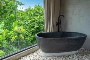a bath tub sitting in front of a window at Kano Uluwatu in Uluwatu