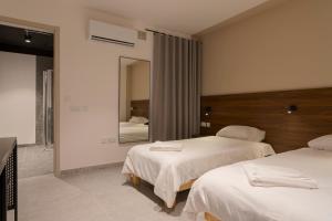 a hotel room with two beds and a mirror at Cora Sun Apart-Hotel in St Paul's Bay +28 photos