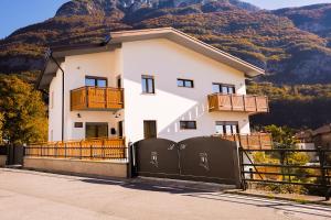 ein weißes Haus mit einem Zaun vor einem Berg in der Unterkunft Antico Borgo in Longarone