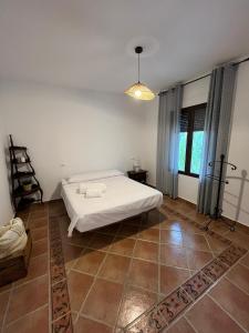a bedroom with a white bed and a large window at Casa de mis sueños Castril in El Batán