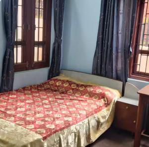 a bedroom with a bed with a red comforter at Bhimalaya in Pātan
