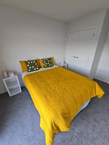 a bedroom with a bed with a yellow blanket at Double Bedroom in Newly Built Townhouse in Wallaceville