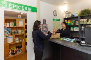 dos mujeres dándose la mano en un mostrador en una tienda en Camping RCN Port l'Epine, en Trélévern