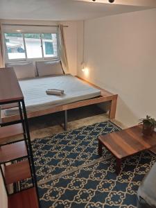 a bed in a small room with a table and a rug at MoovInn Garden Guesthouse in Koh Tao
