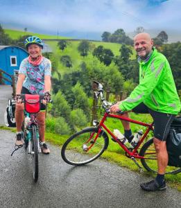 Ein Mann und eine Frau auf einer Straße auf Fahrrädern in der Unterkunft Wild Valley Bunkhouse in Llanrhaeadr-ym-Mochnant