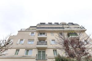 ein hohes Gebäude in Braun mit einem Balkon in der Unterkunft Venturia - 23 min en train de Paris in Le Plessis-Bouchard