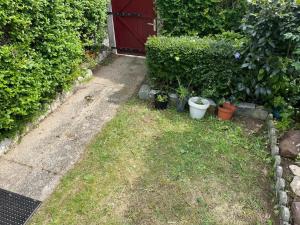 een tuin met potplanten en een rode deur bij Maison confortable avec terrasse à Courseulles-sur-Mer in Courseulles-sur-Mer