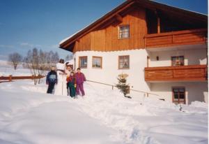 un gruppo di persone in piedi sulla neve di fronte a una cabina di Ferienwohnung Max und Klaudia Müller a Drachselsried