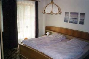 a bedroom with a bed with a wooden headboard and a window at Ferienwohnung Max und Klaudia Müller in Drachselsried